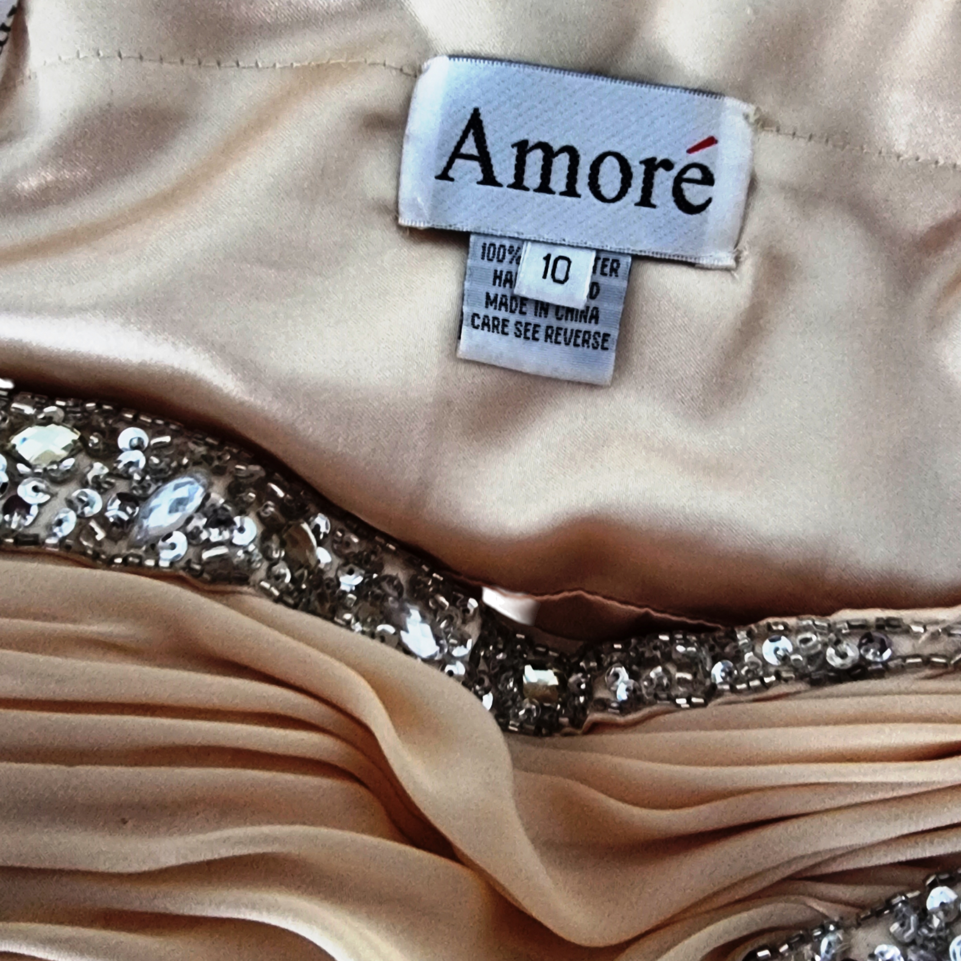 Close-up of a beige fabric with a 'Amore' label and sequin details.