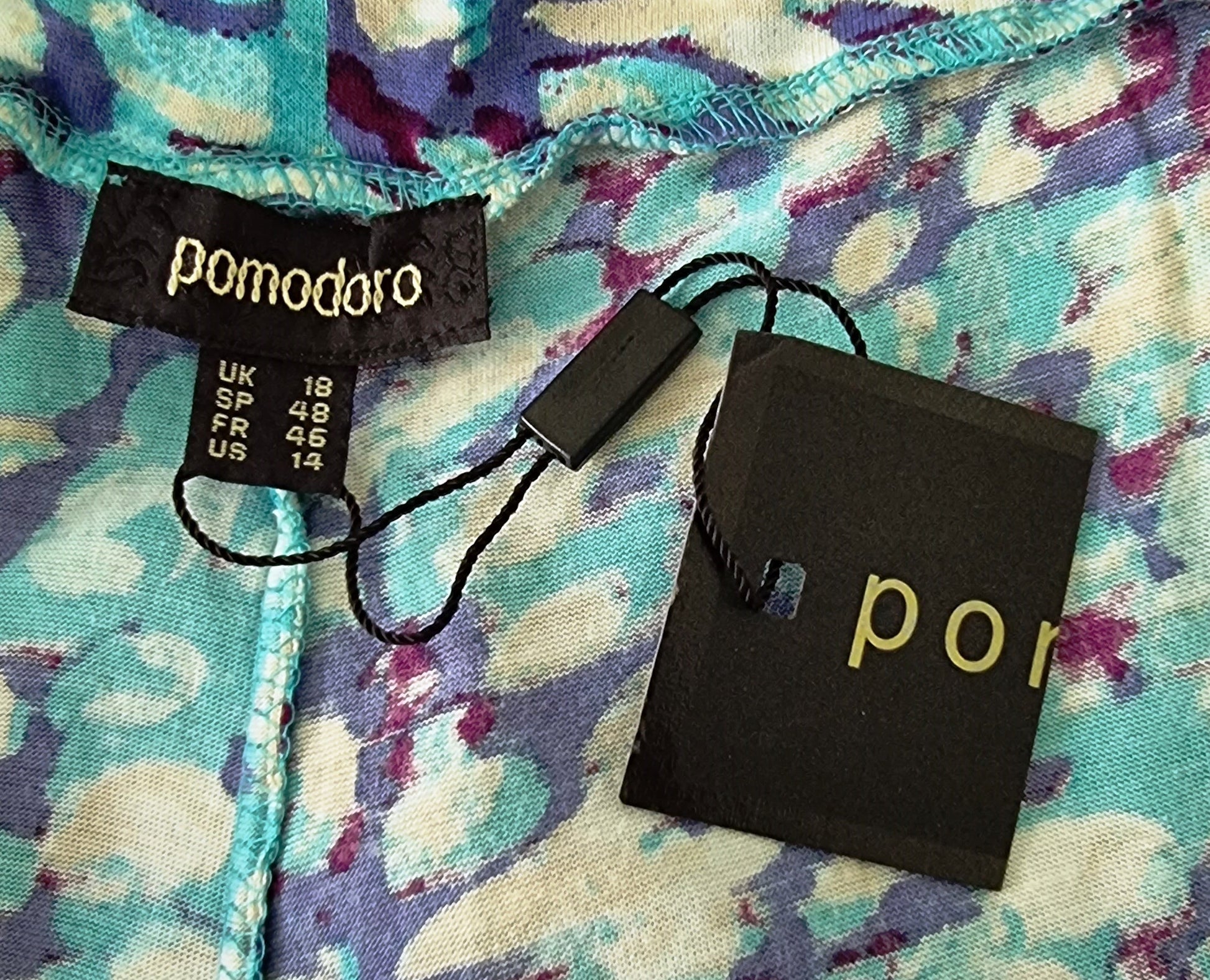Close-up of a patterned fabric with a pomodoro label and packaging.