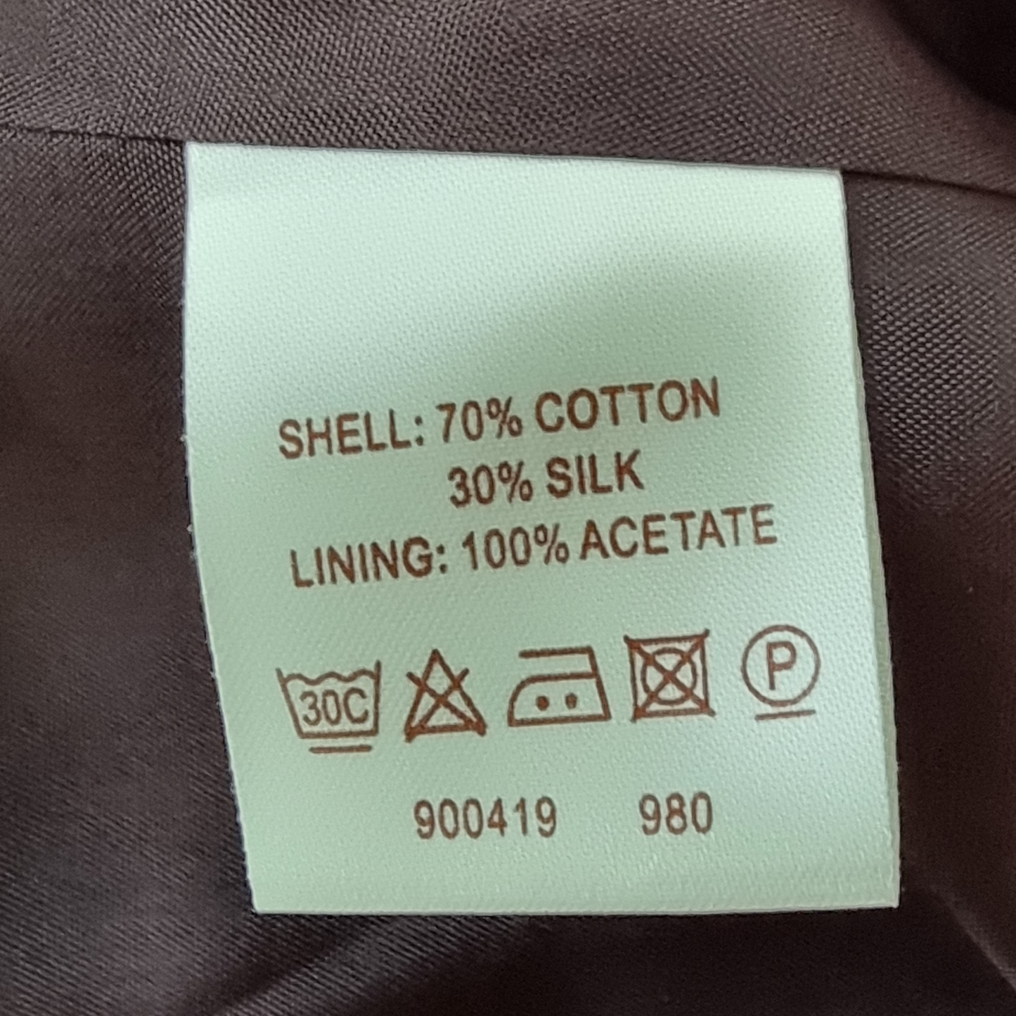 Clothing label with material composition and care instructions on a fabric background