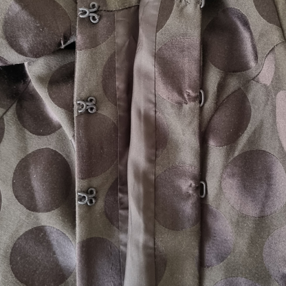 Close-up of a jacket with a pattern of large, dark circles on a light background.