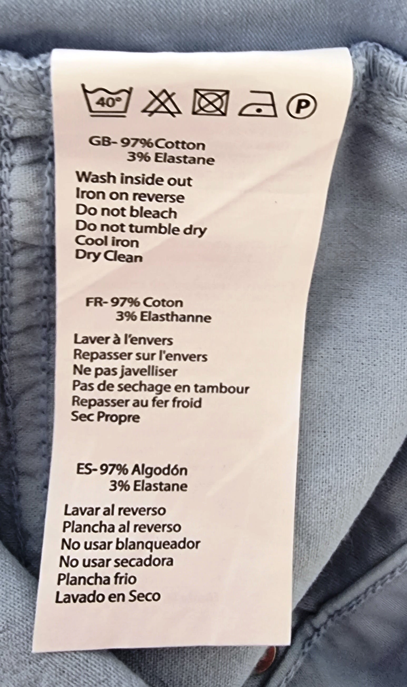 Clothing label with care instructions on a gray fabric background