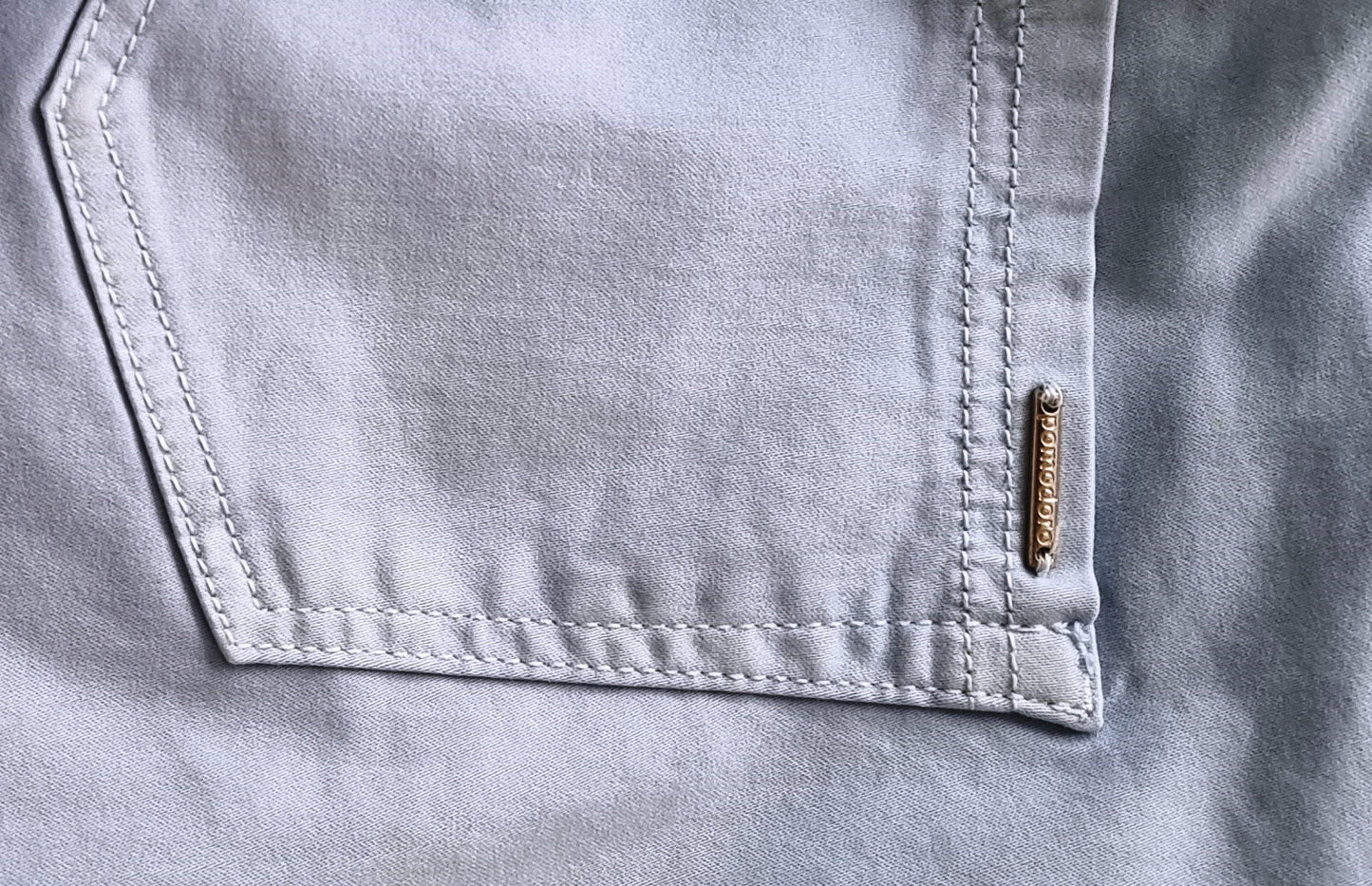 Close-up of a pocket on a light gray shirt with a brand label.