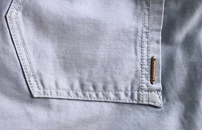 Close-up of a pocket on a light gray shirt with a brand label.
