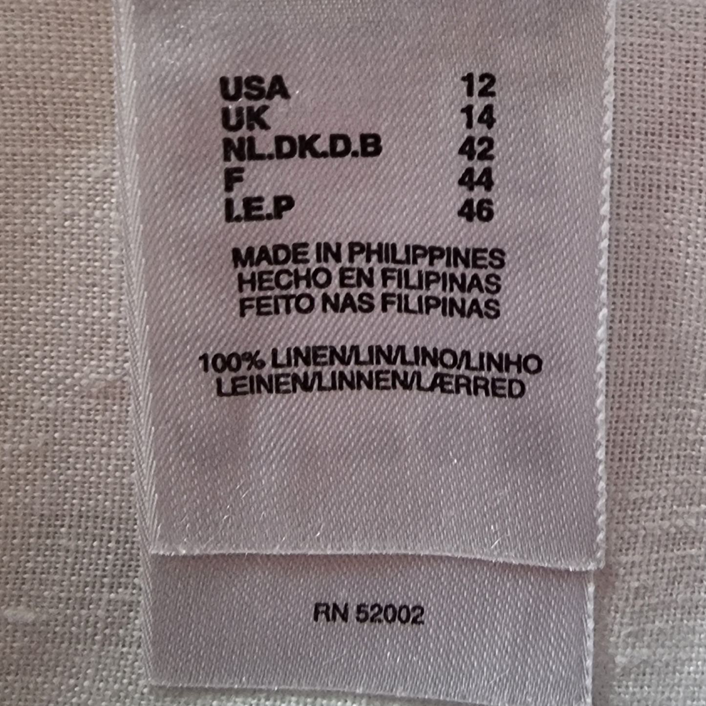 Fabric label with size and origin information on a textured fabric background