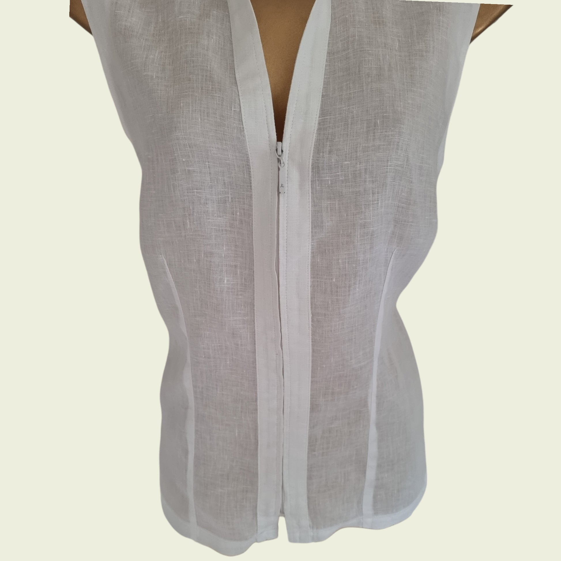 White sleeveless top with zipper on a beige background