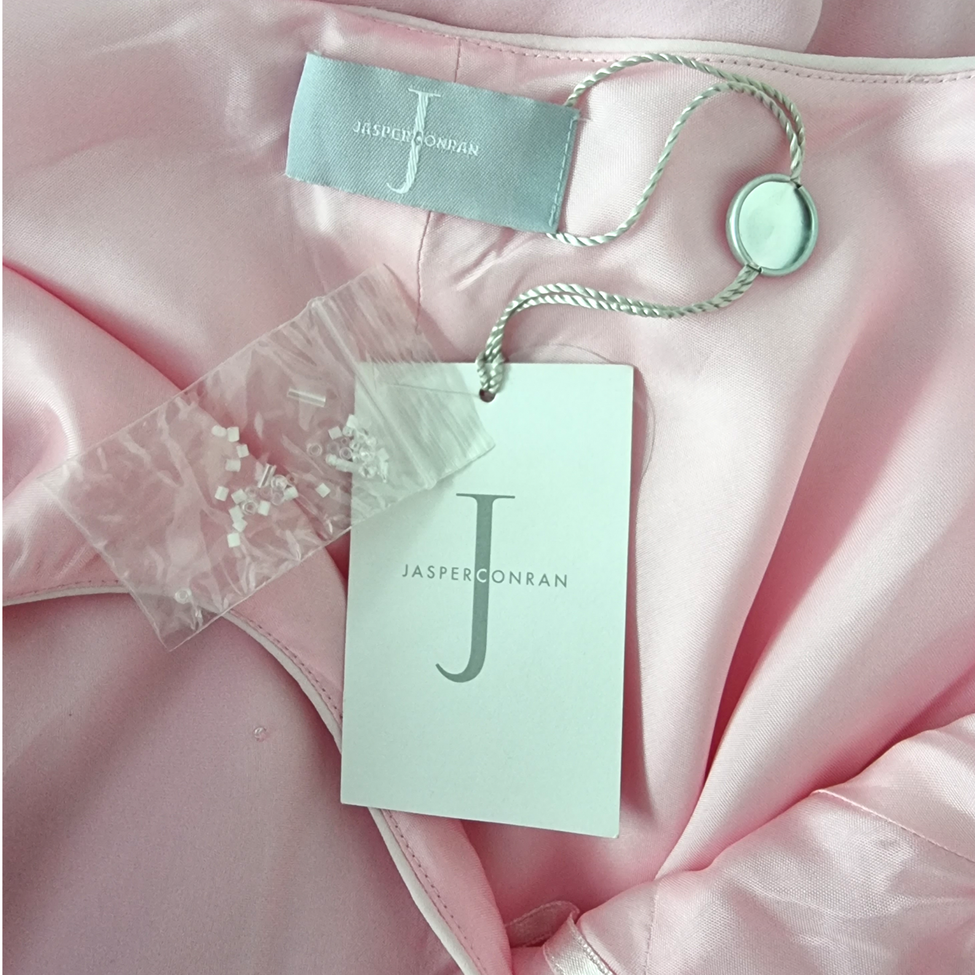 Pink fabric with Jasper Conran tags and a button on a pink background