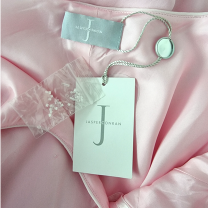 Pink fabric with Jasper Conran tags and a button on a pink background