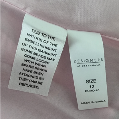 Clothing label with warning and size information on a pink garment.