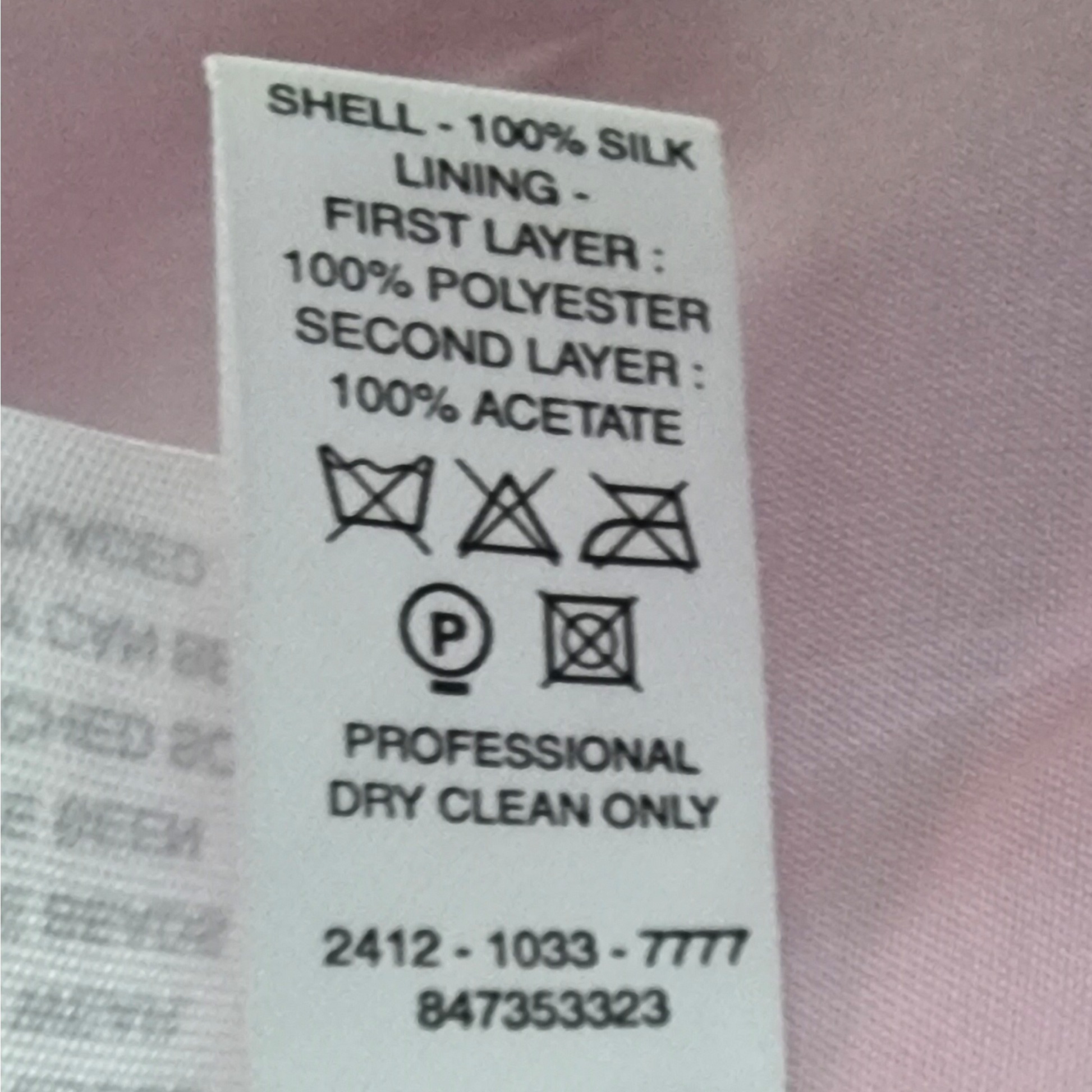 Clothing label with fabric composition and care instructions on a pink fabric background