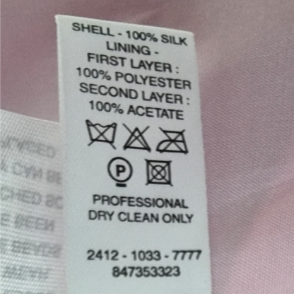 Clothing label with fabric composition and care instructions on a pink fabric background