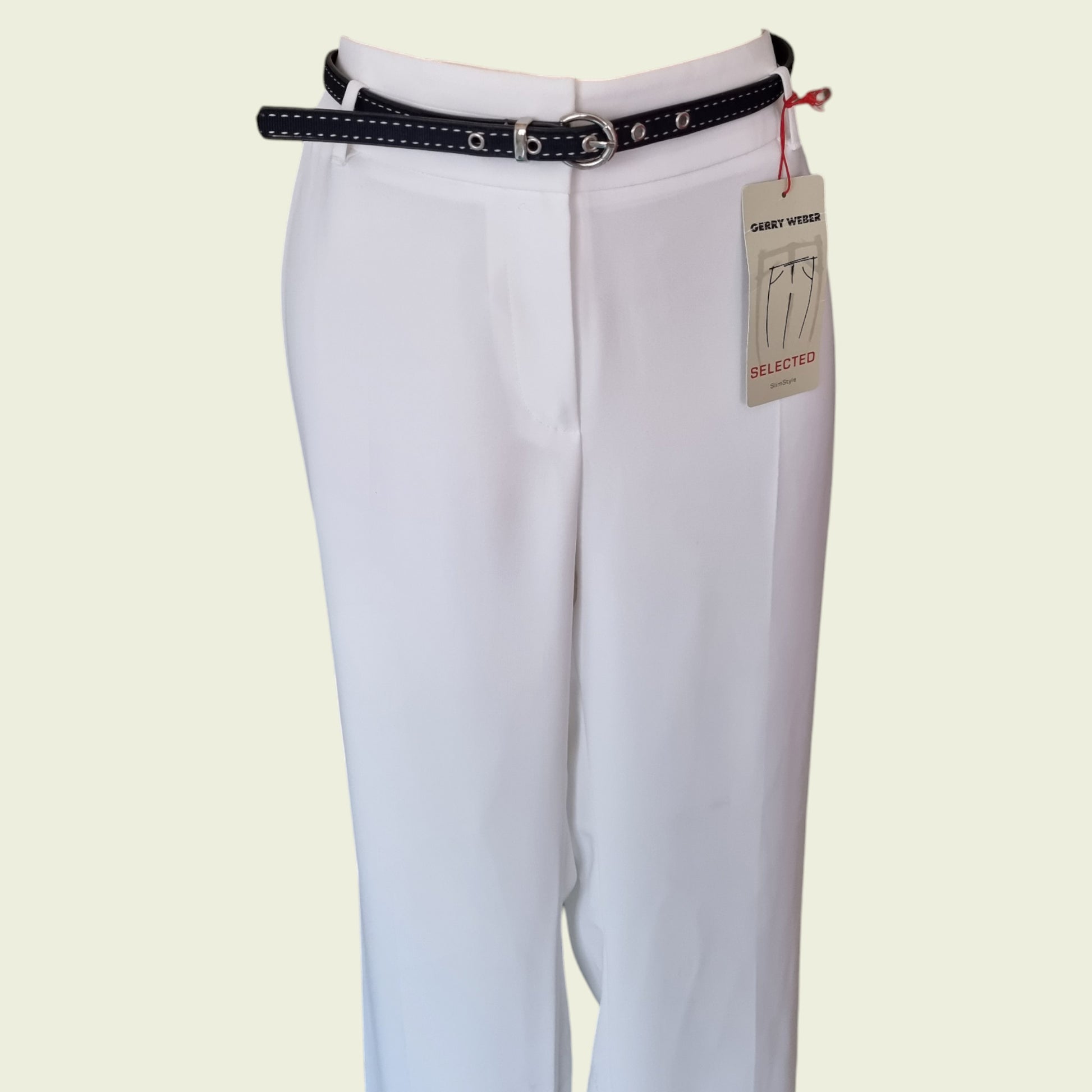 White pants with a navy belt and visible brand tag on a light beige background