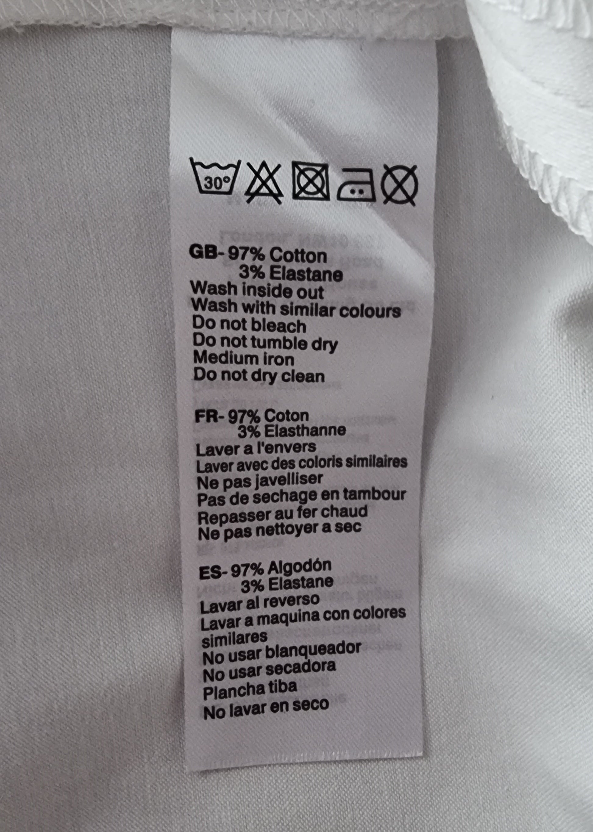 Close-up of a fabric label with washing instructions on a light gray background