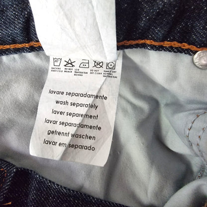Close-up of a clothing label on denim fabric with washing instructions.