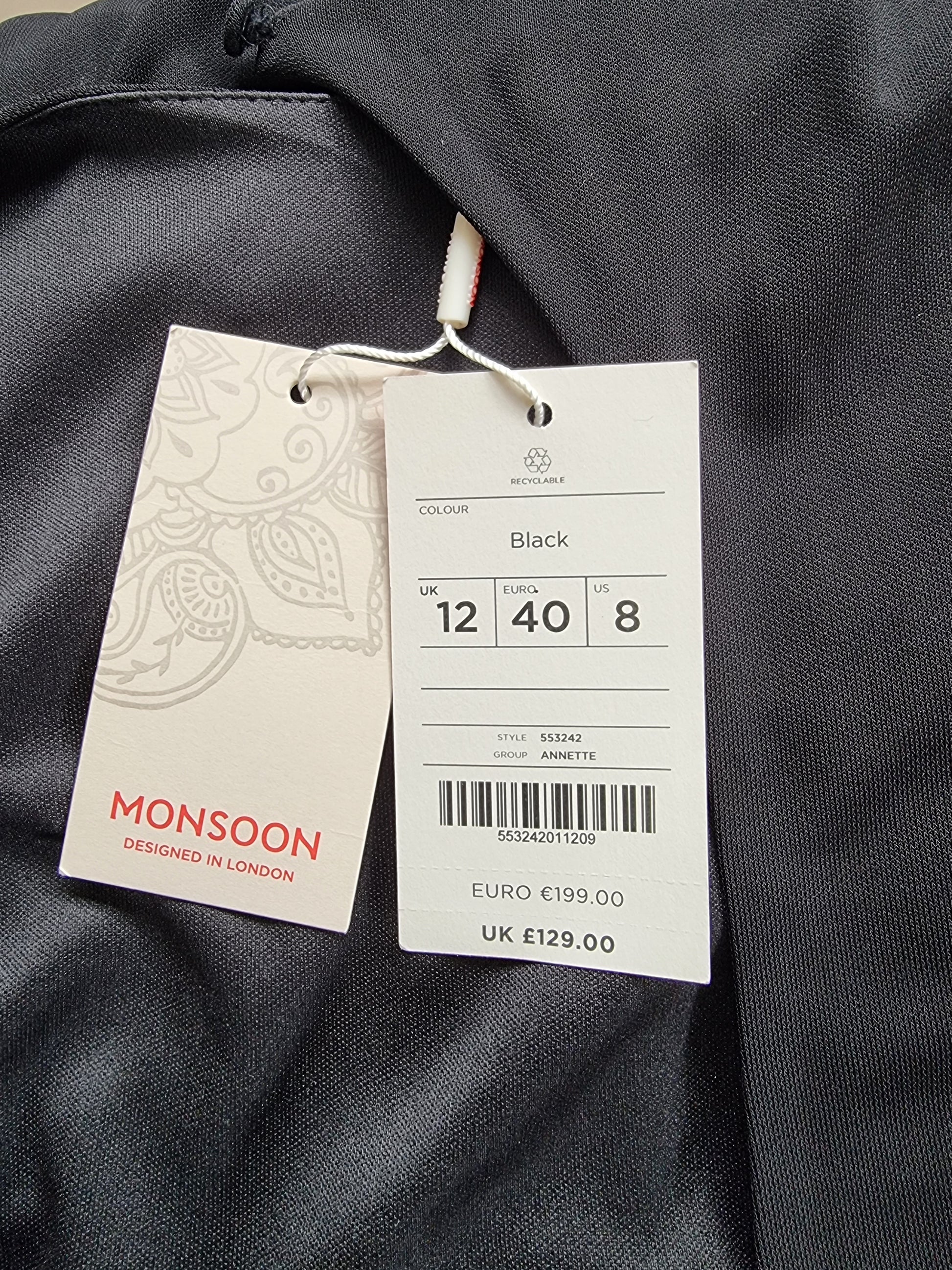 Clothing tag with size and brand information on a dark fabric background