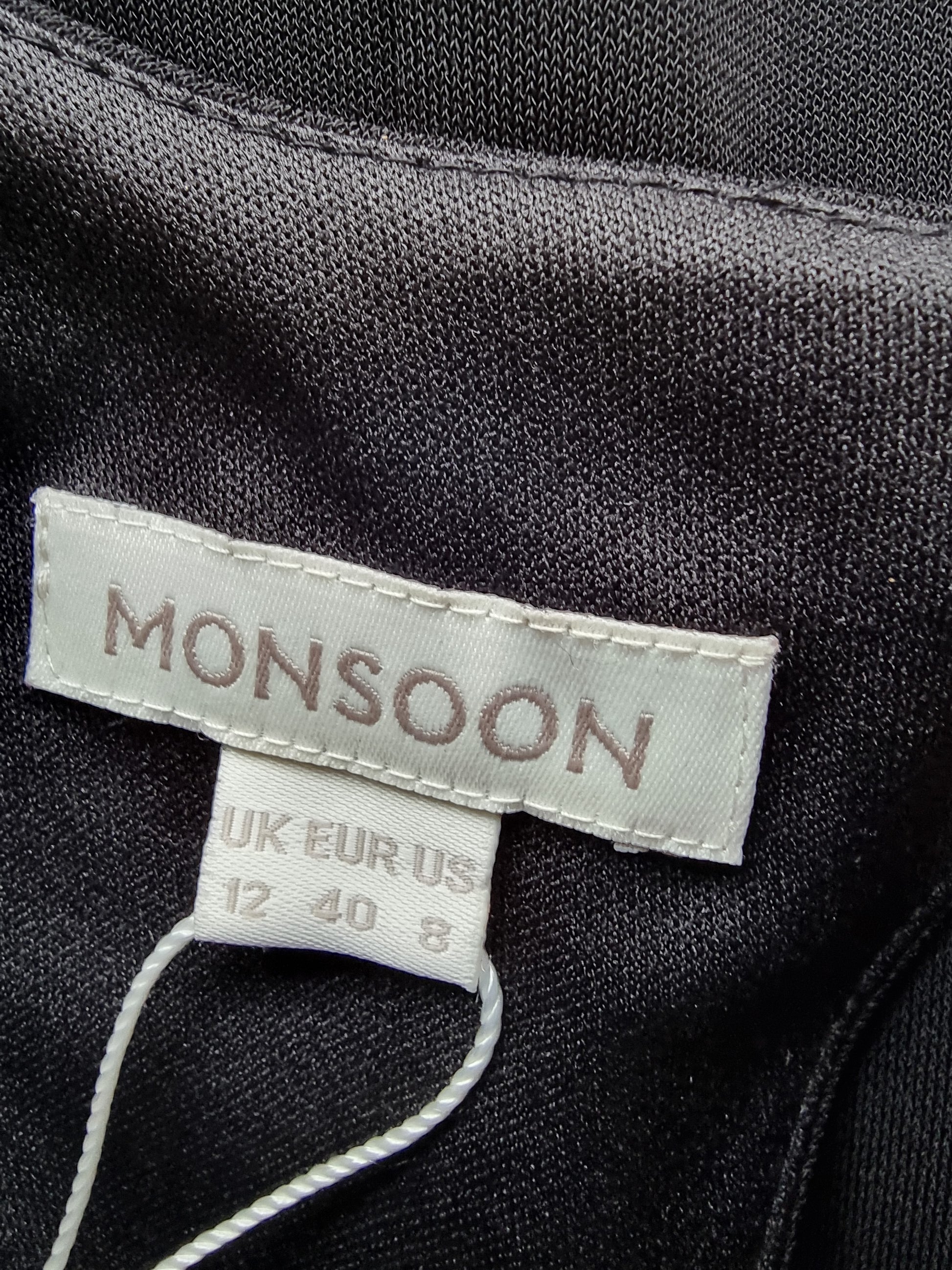 Close-up of a 'Monsoon' label on dark fabric