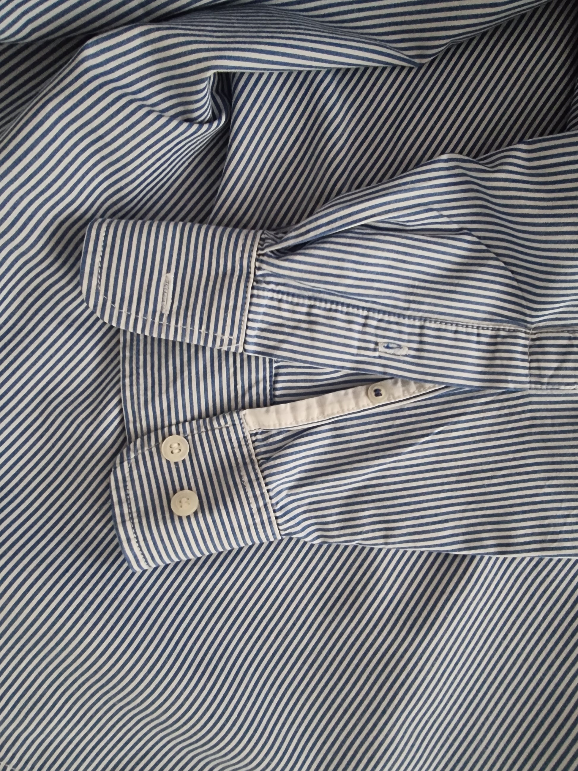 Close-up cuffs of a blue and white striped shirt.