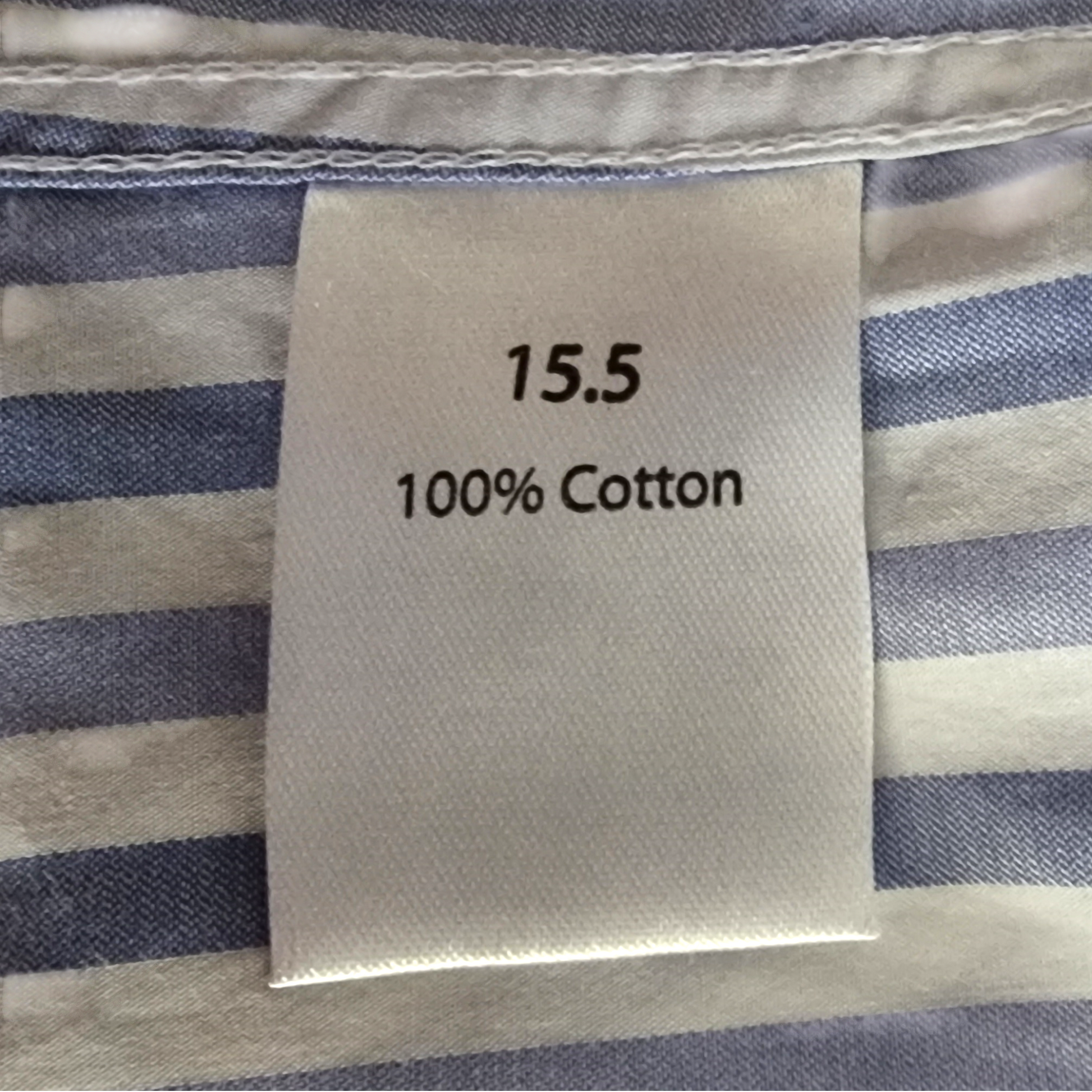 Label on striped fabric indicating size 15.5 and 100% cotton