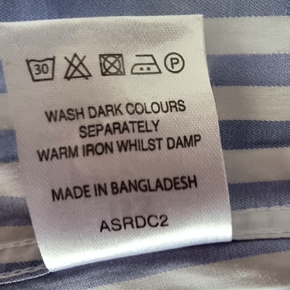 Clothing label with washing instructions and product details on a striped fabric background