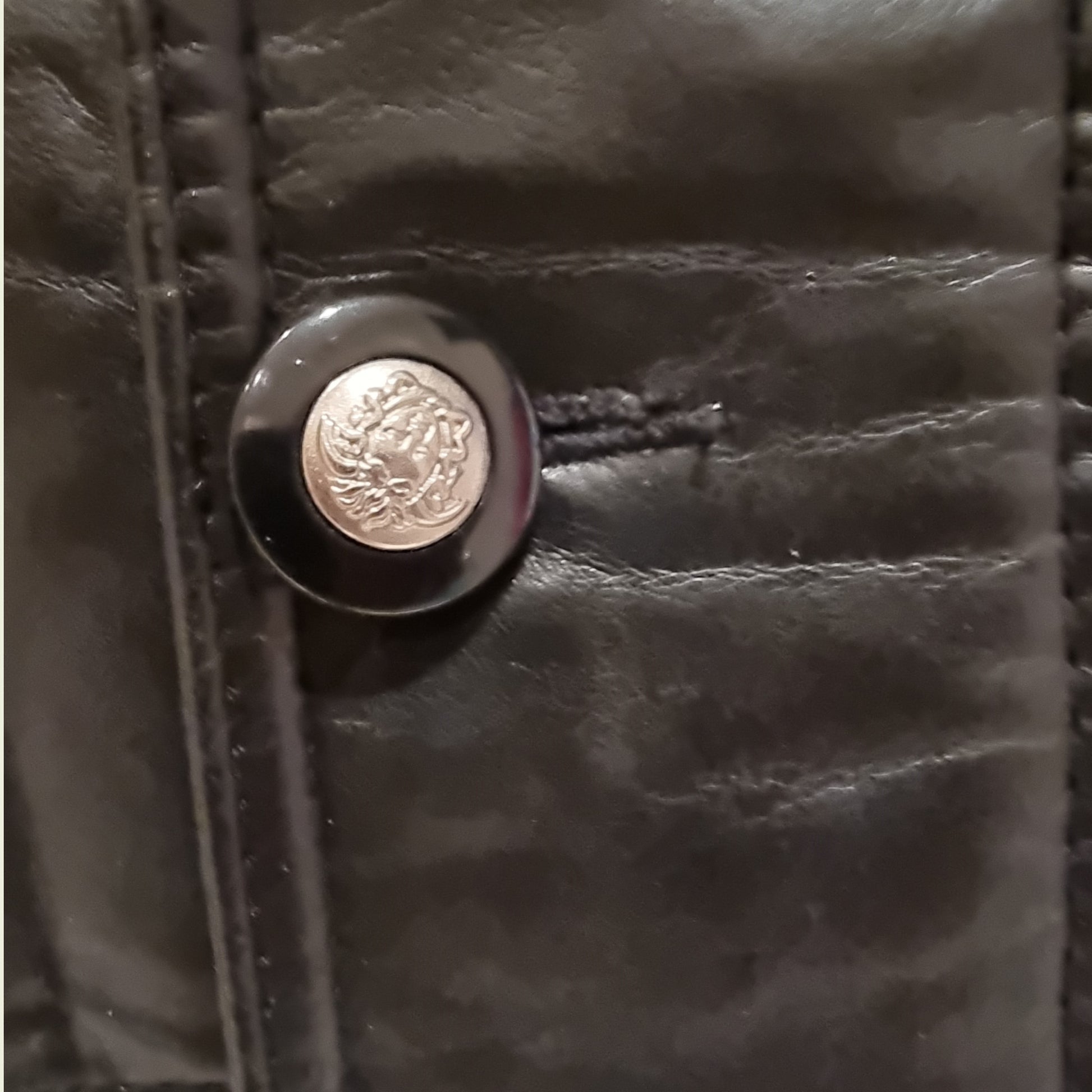 Close-up of a black leather button with a metallic emblem on a dark background