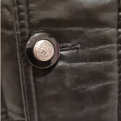 Close-up of a black leather button with a metallic emblem on a dark background