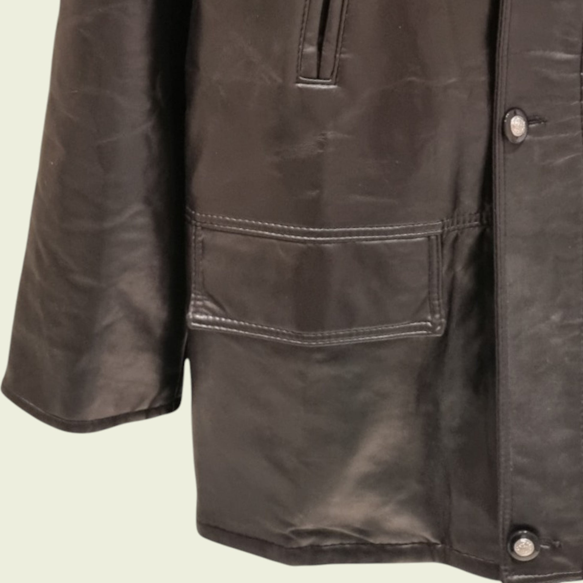Close-up of a Black leather jacket with a pocket and buttons on a beige background