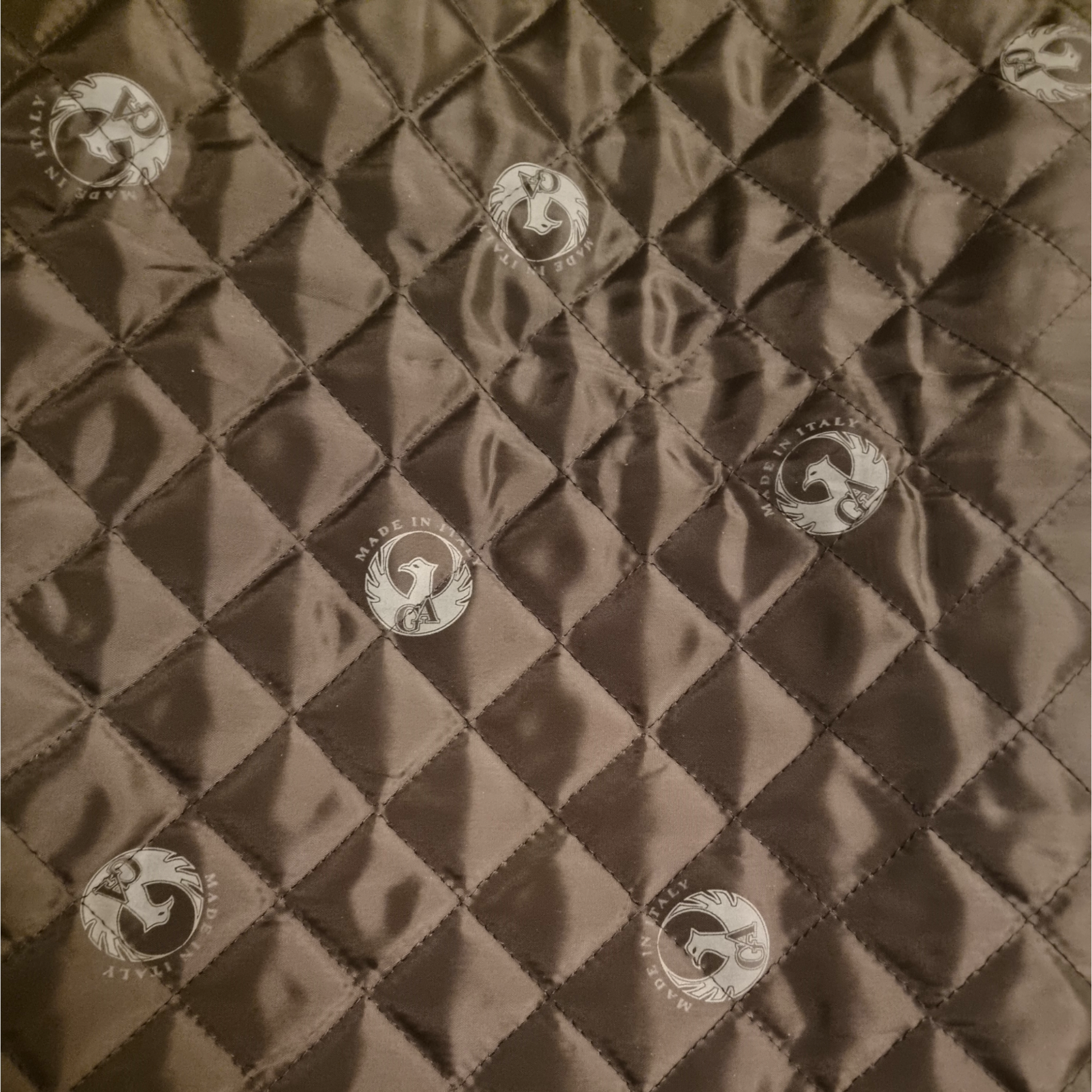 Quilted fabric with diamond pattern and button-like embellishments on a brown background