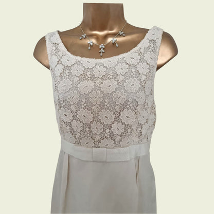 Mannequin wearing a cream dress with embroidered bodice on beige background