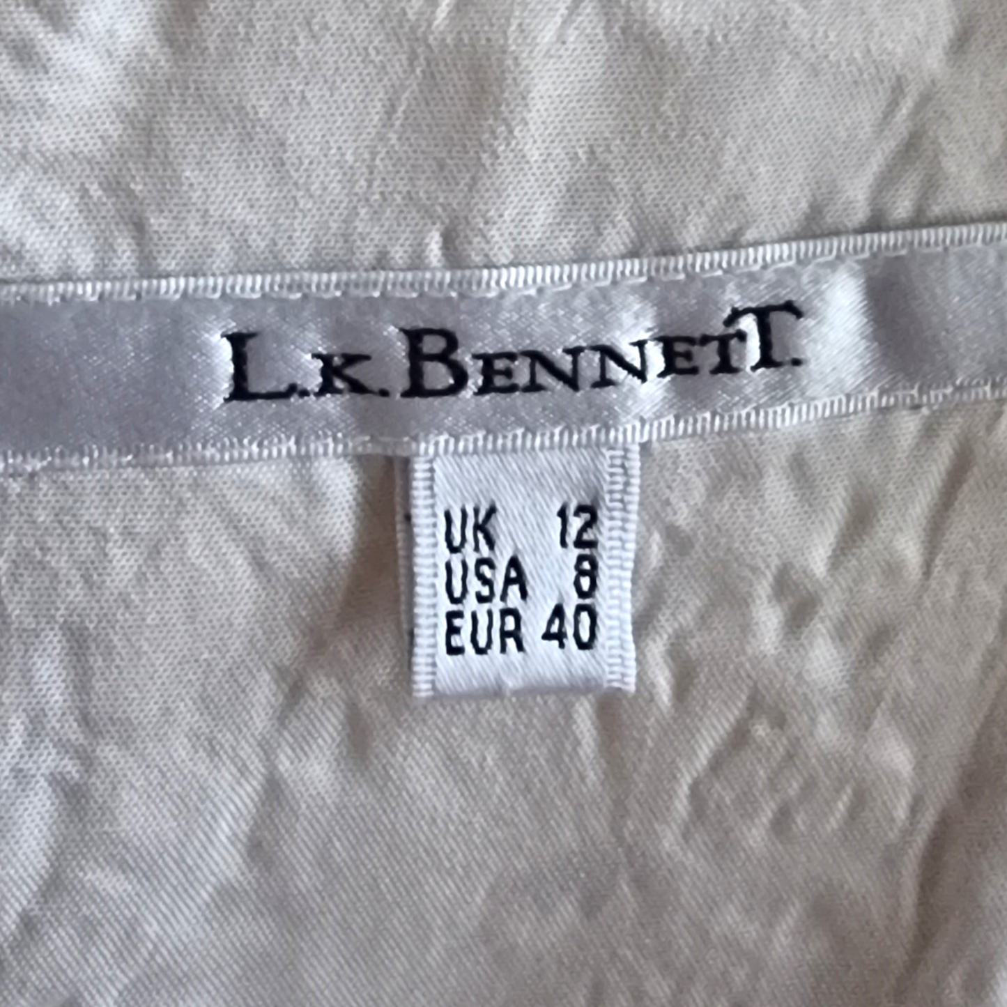 Dress label with L.K.BENNET and size details on cream background