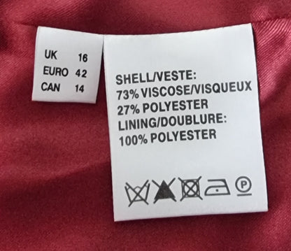 Clothing label with size chart and material information on a red fabric background