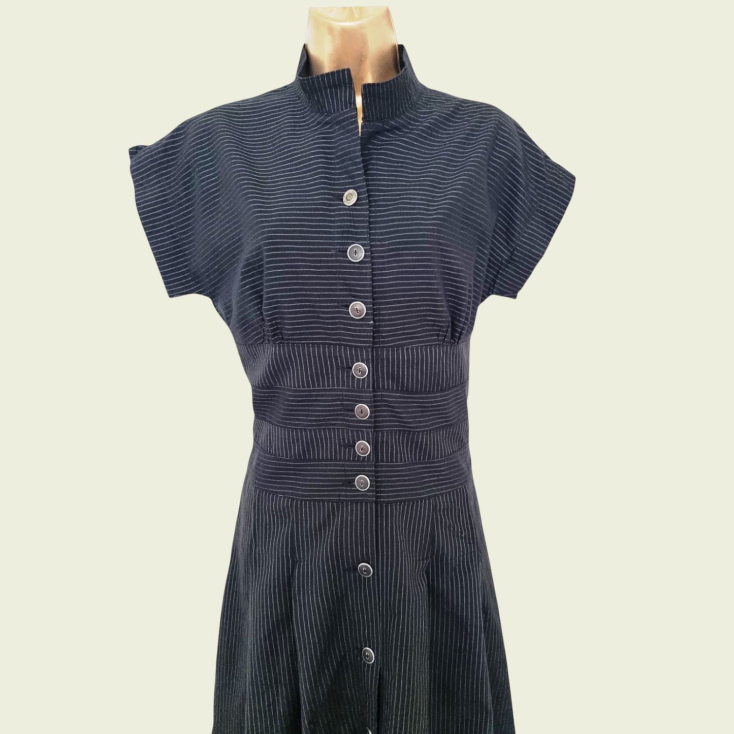 Black ribbed dress with button details on a mannequin against a beige background