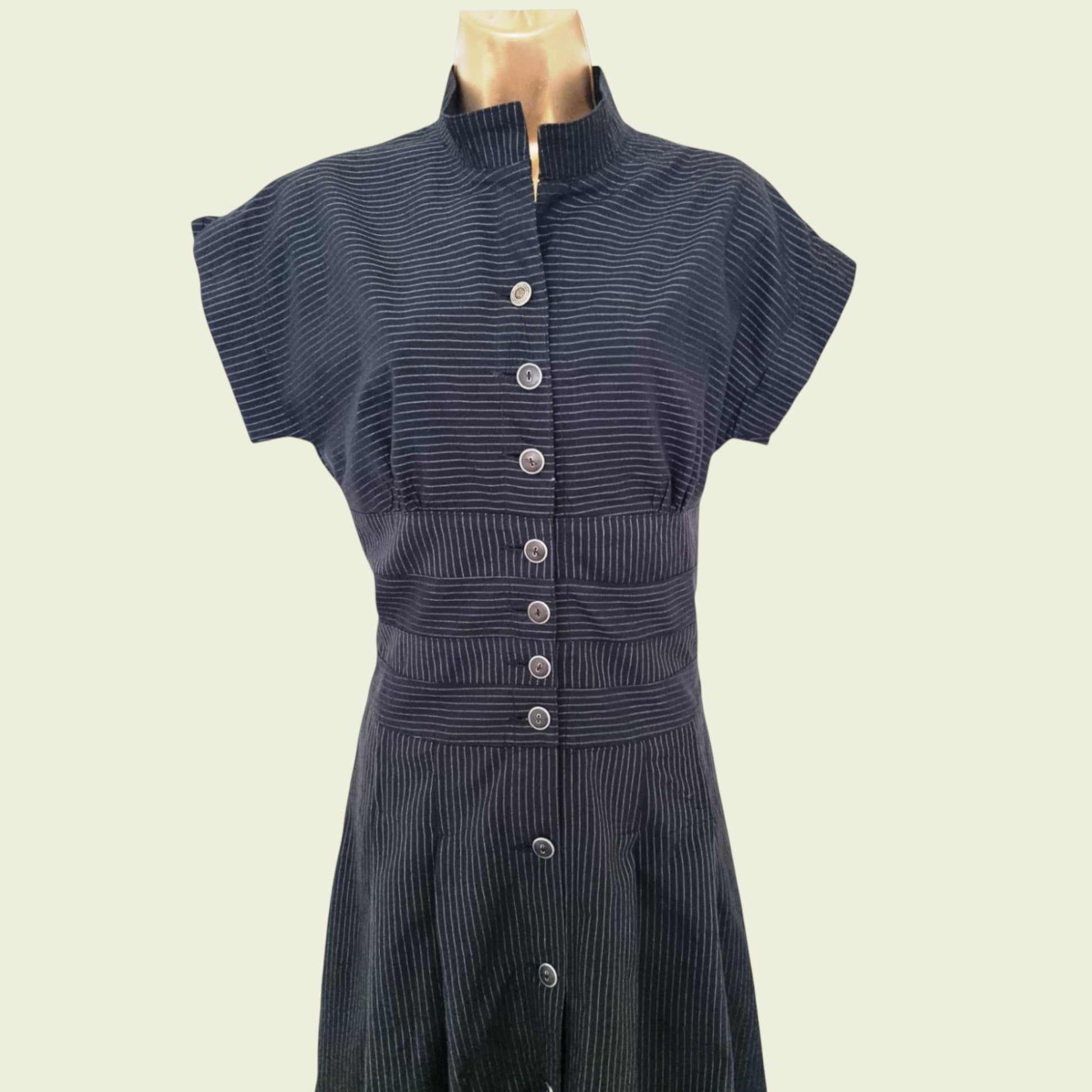 Black ribbed dress with button details on a mannequin against a beige background