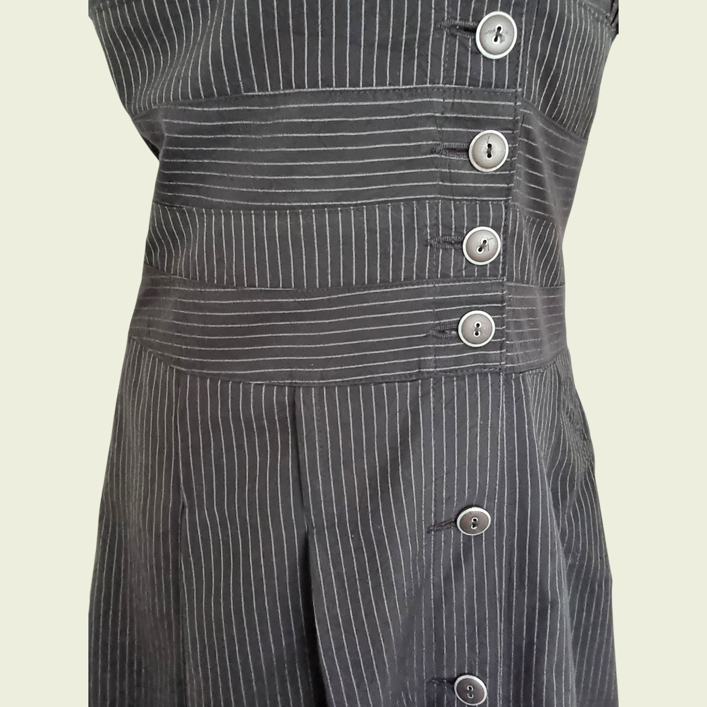 Black pinstripe dress with buttons on a beige background