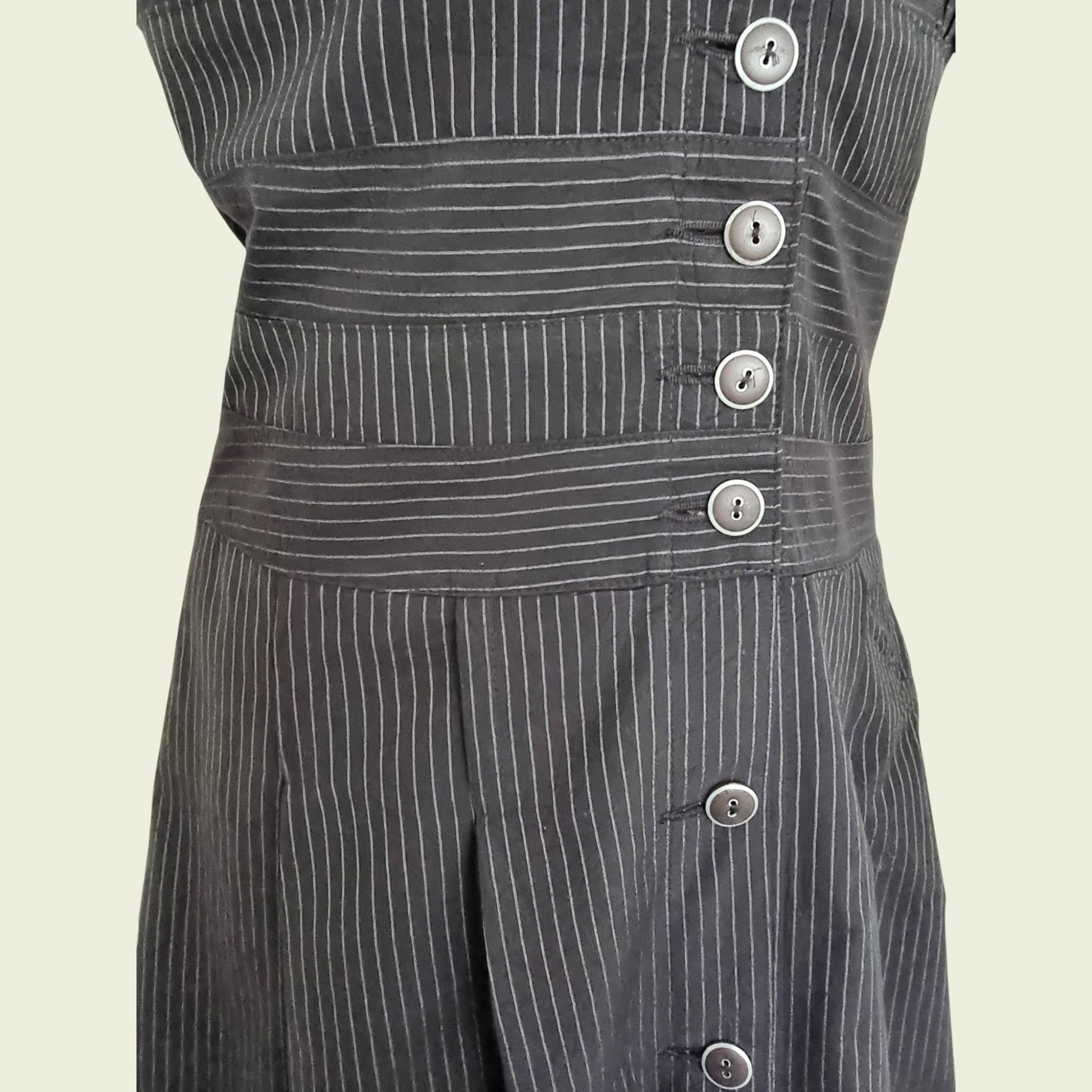 Black pinstripe dress with buttons on a beige background