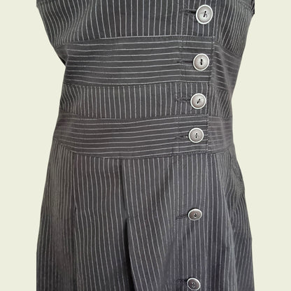 Black pinstripe dress with buttons on a beige background