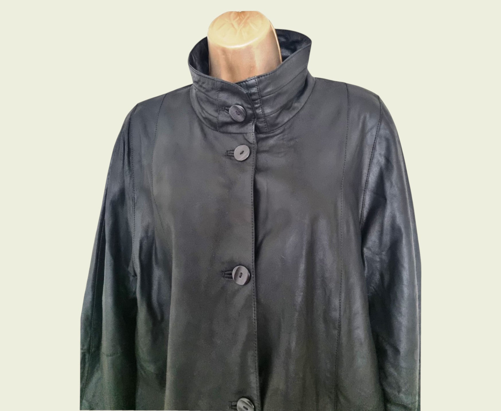 Black coat on a mannequin against a beige background