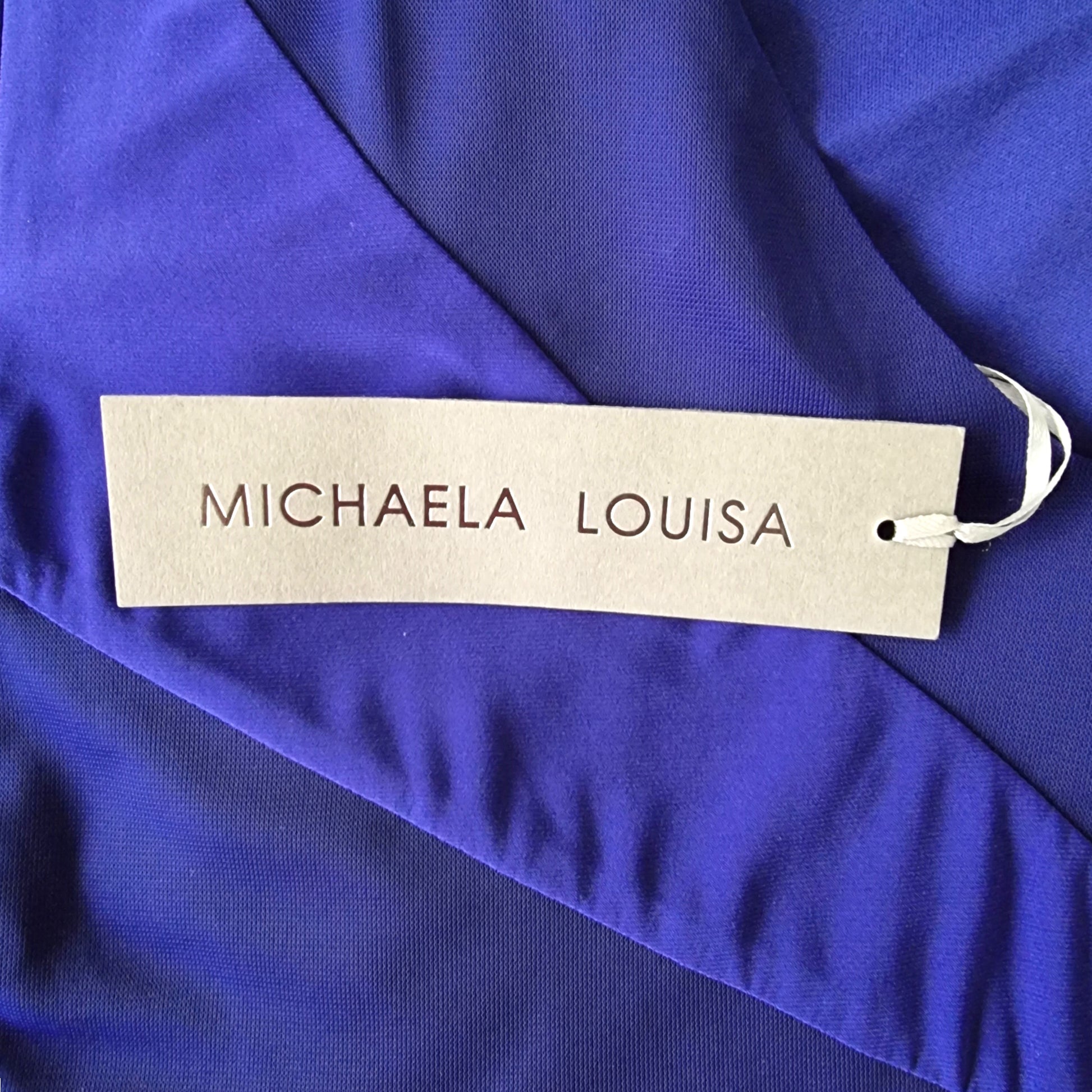Name tag with 'MICHAELA LOUISA' on a blue fabric background