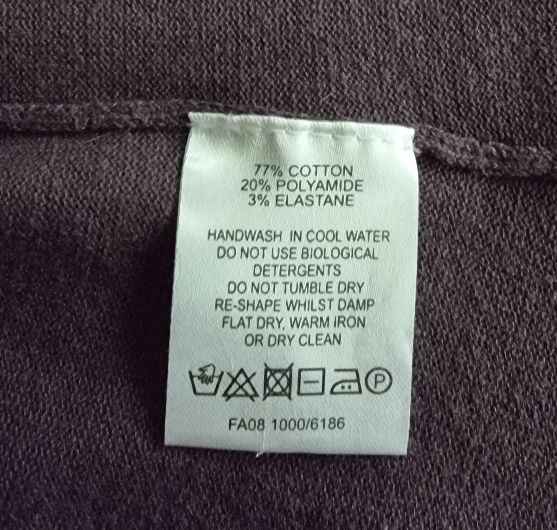 Clothing label with fabric composition and care instructions on a dark fabric background