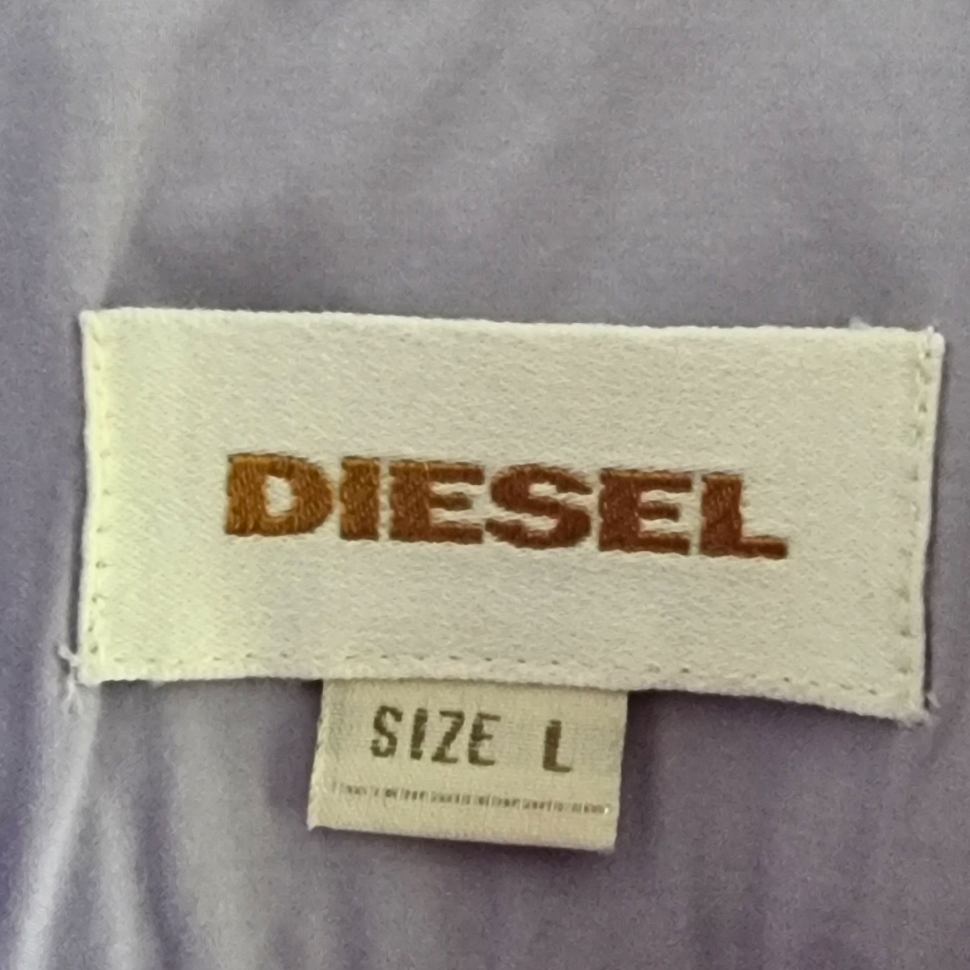 Garment label with 'Diesel' and size details on lilac background