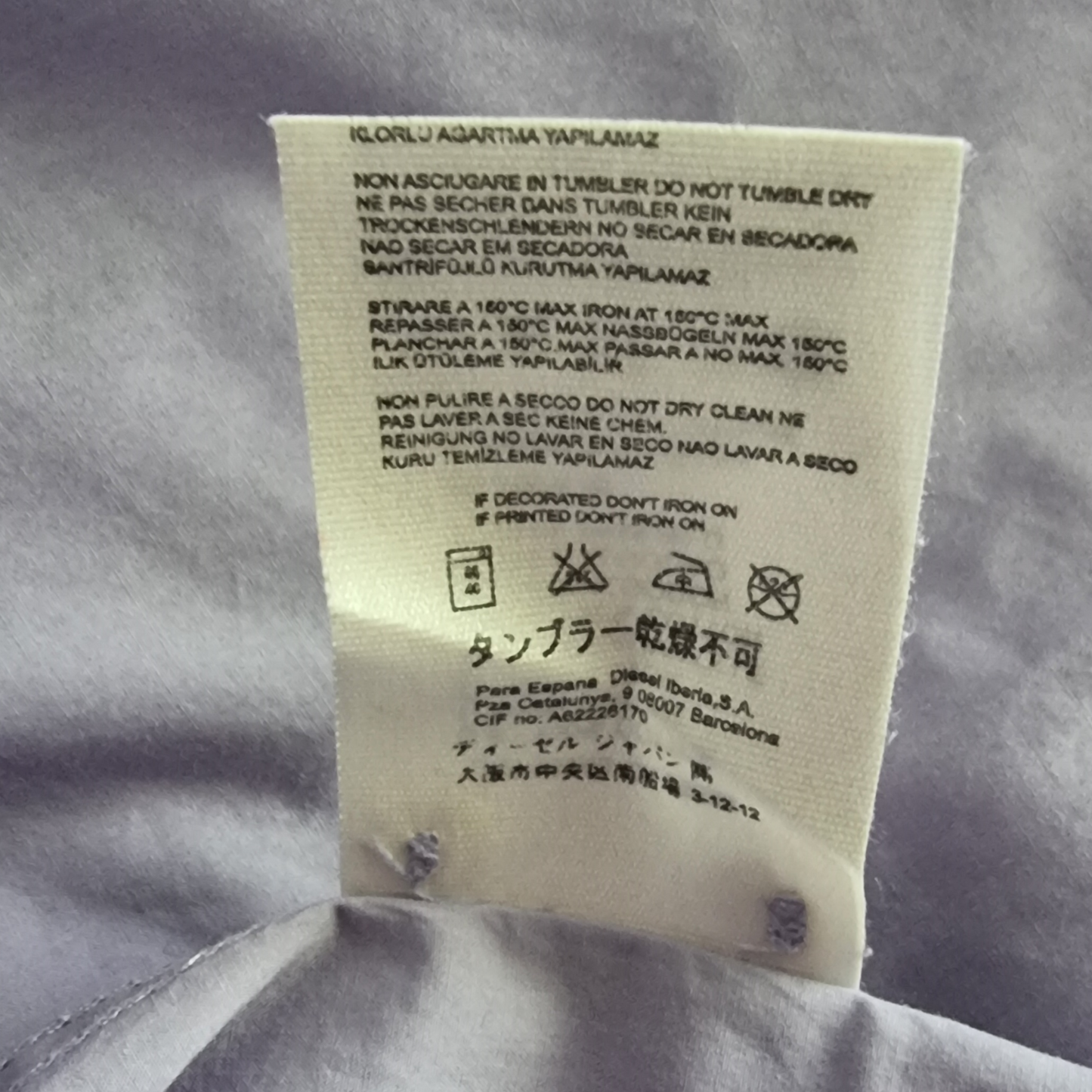 Garment label with care instructions on lilac background