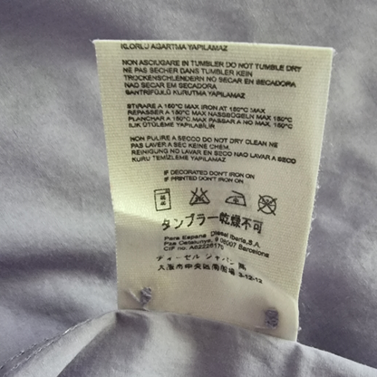 Garment label with care instructions on lilac background