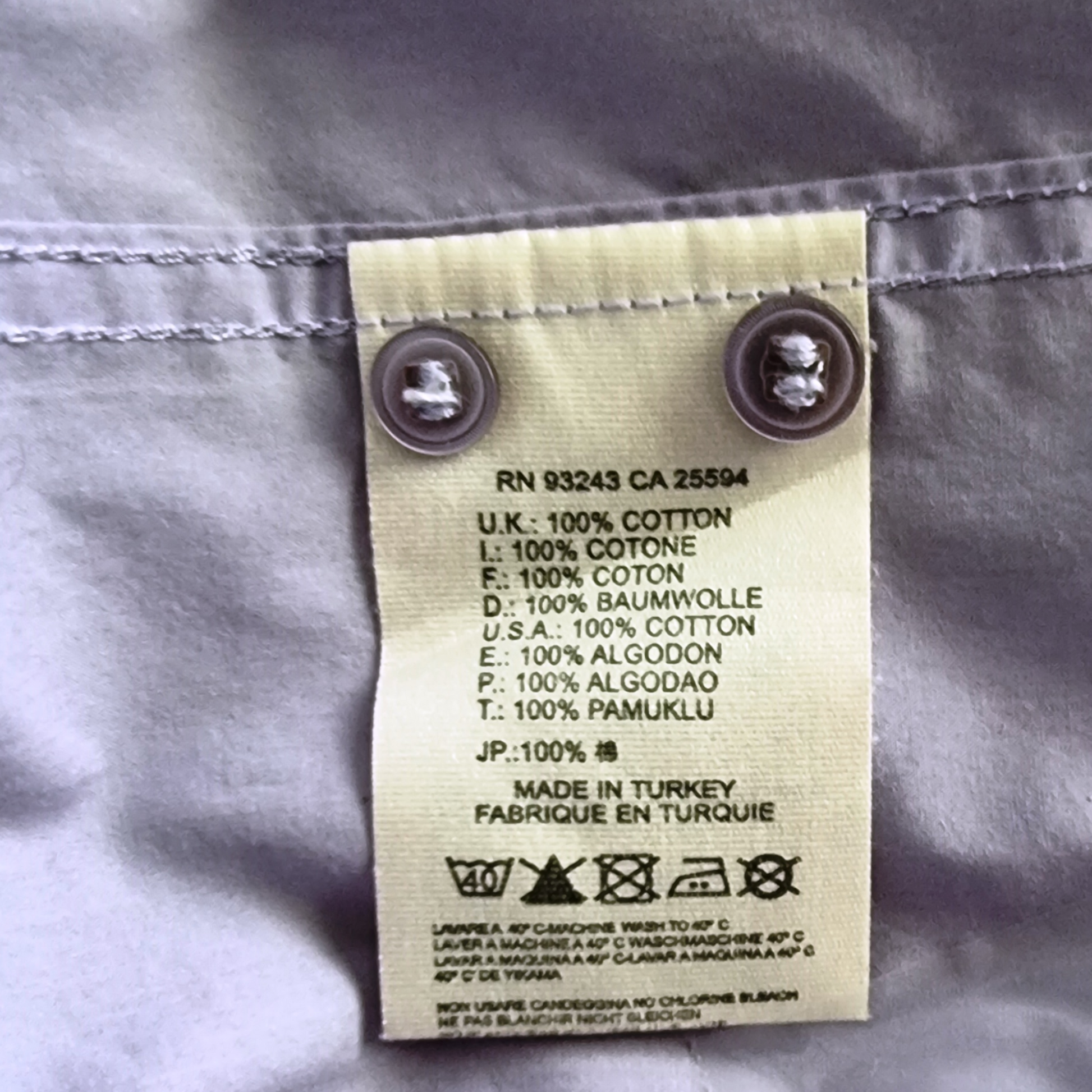 Garment label with fabric content and care instructions on lilac background
