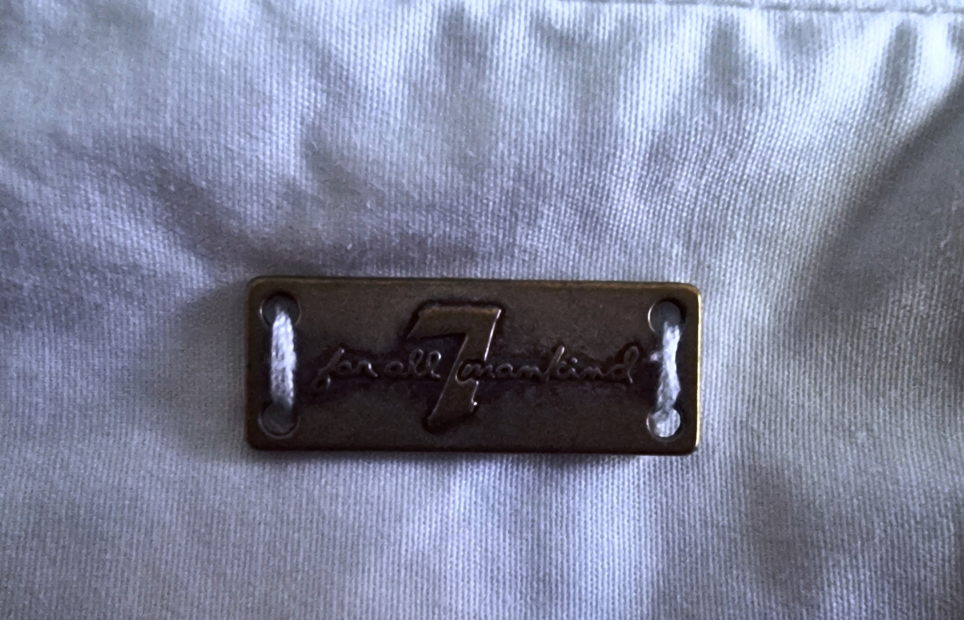 Metallic badge with 'Fender' logo on a light gray fabric background
