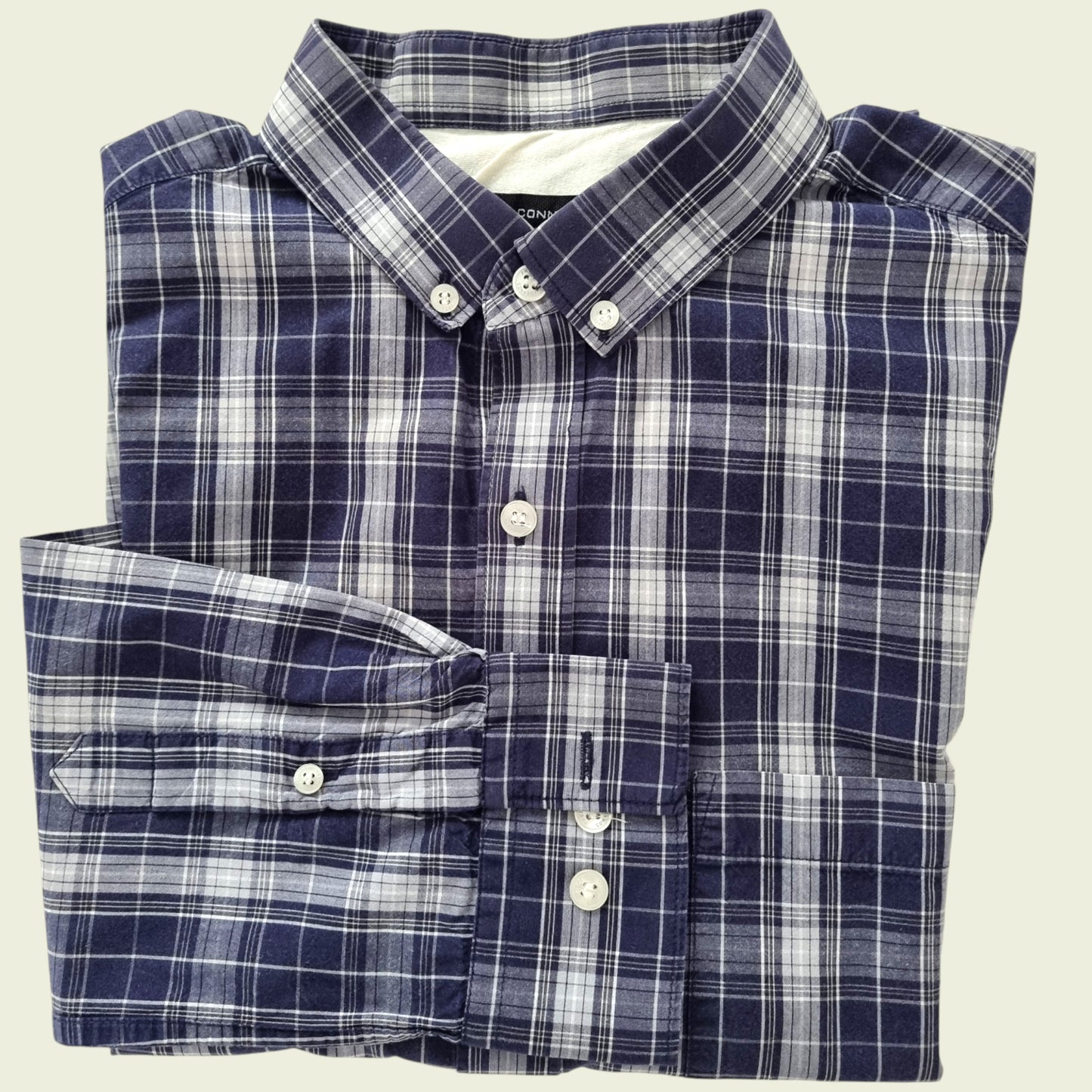 Folded blue and white plaid shirt on a beige background