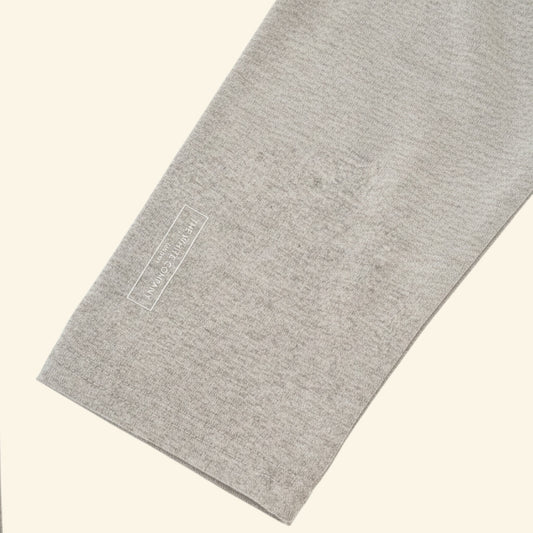 A close-up of a light sleeve or cuff, angled diagonally on a solid cream background. A small white rectangular brand label reading 'The White Company' is printed onto the fabric.