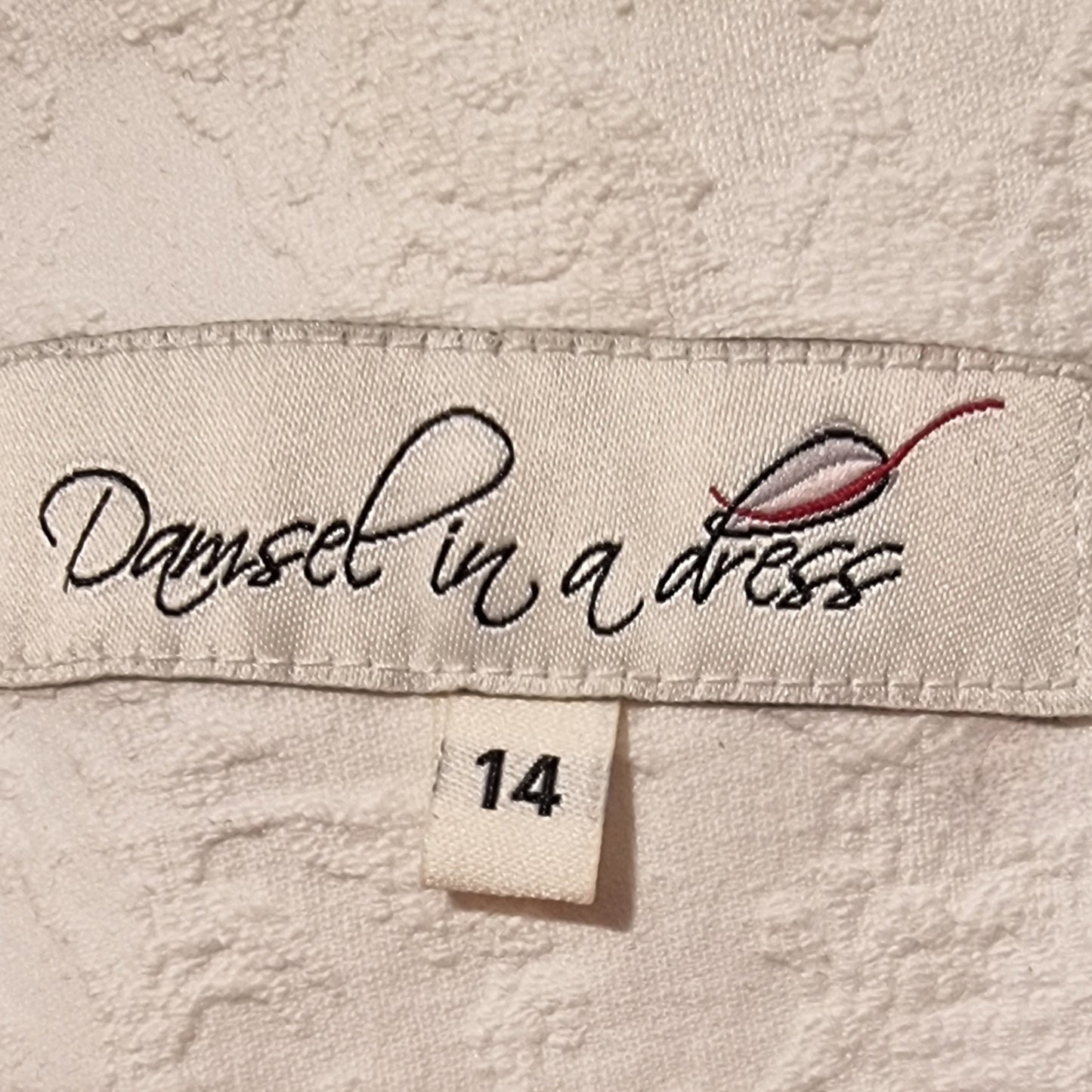 Label with 'Damsel in a Dress' branding on a textured fabric background