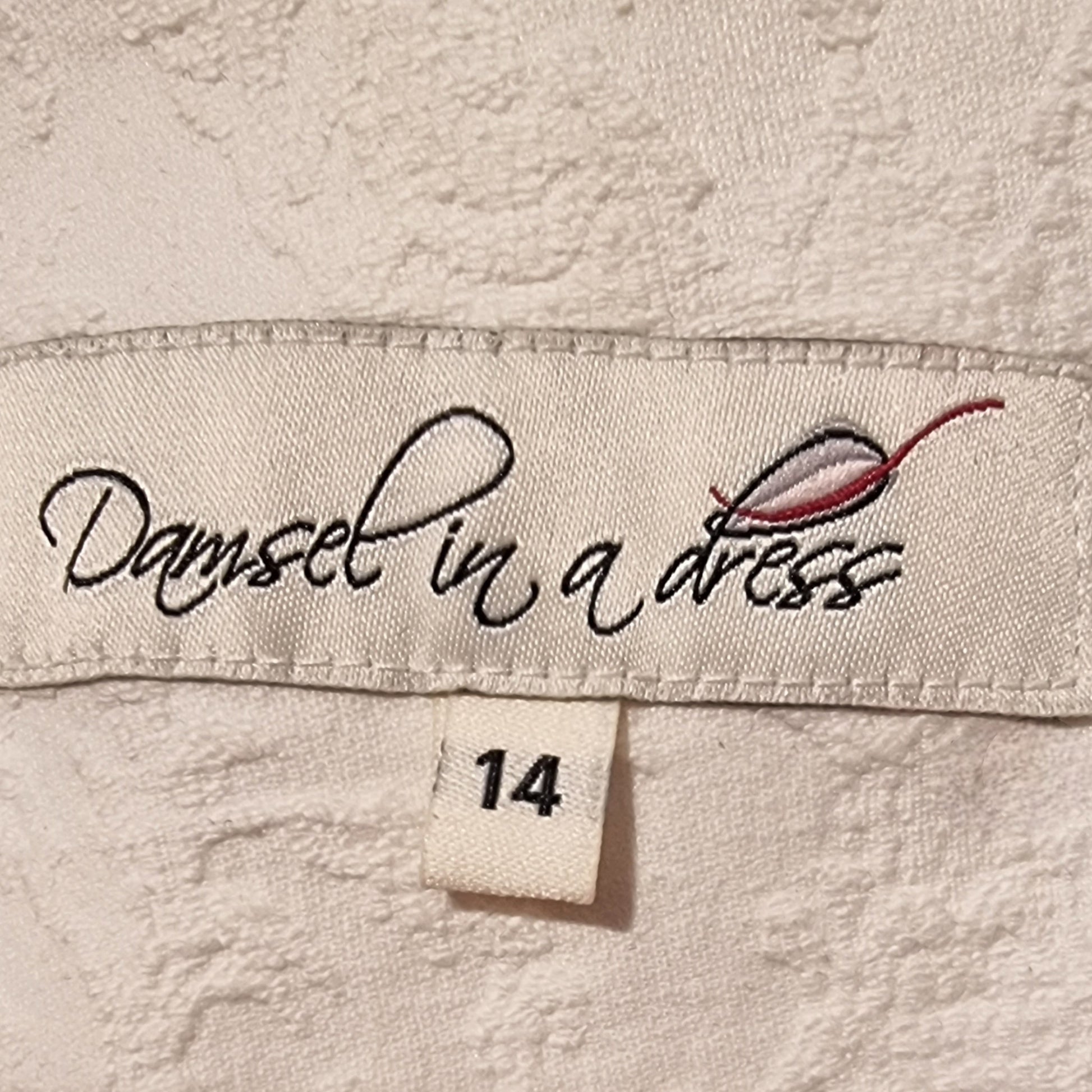 Label with 'Damsel in a Dress' branding on a textured fabric background