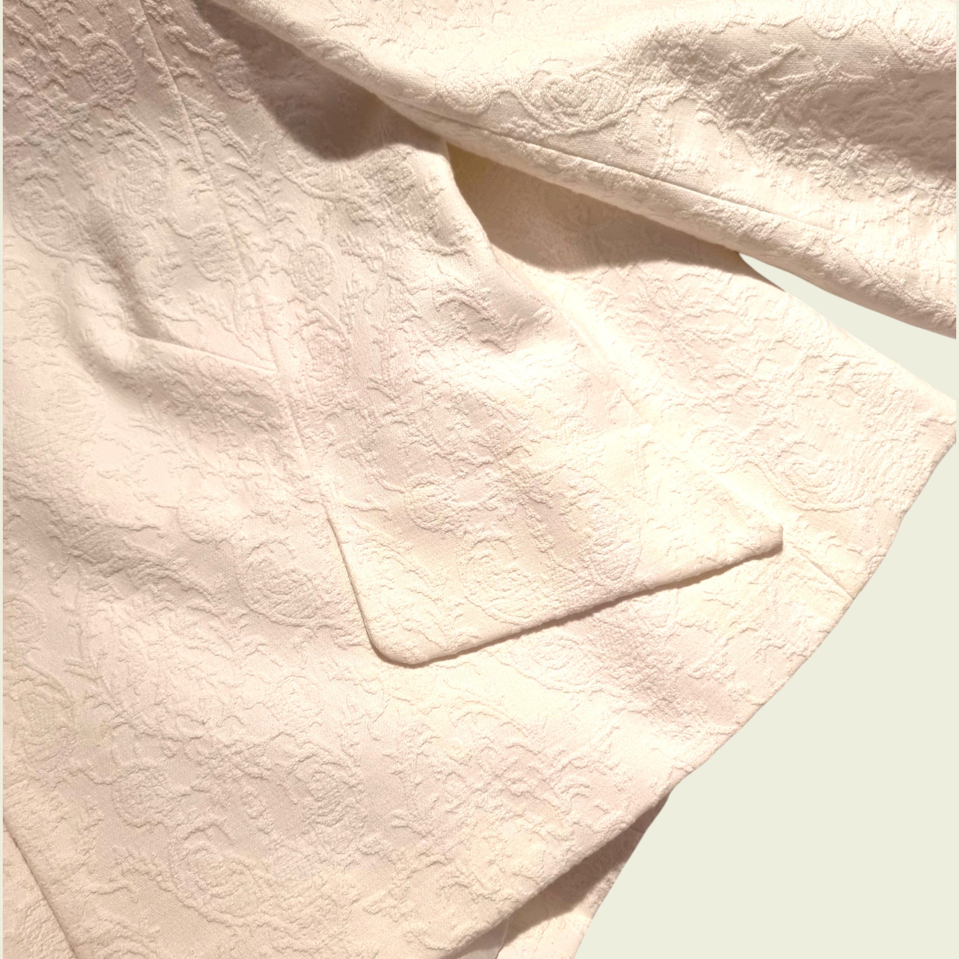 Close-up of textured white fabric with a pocket detail.