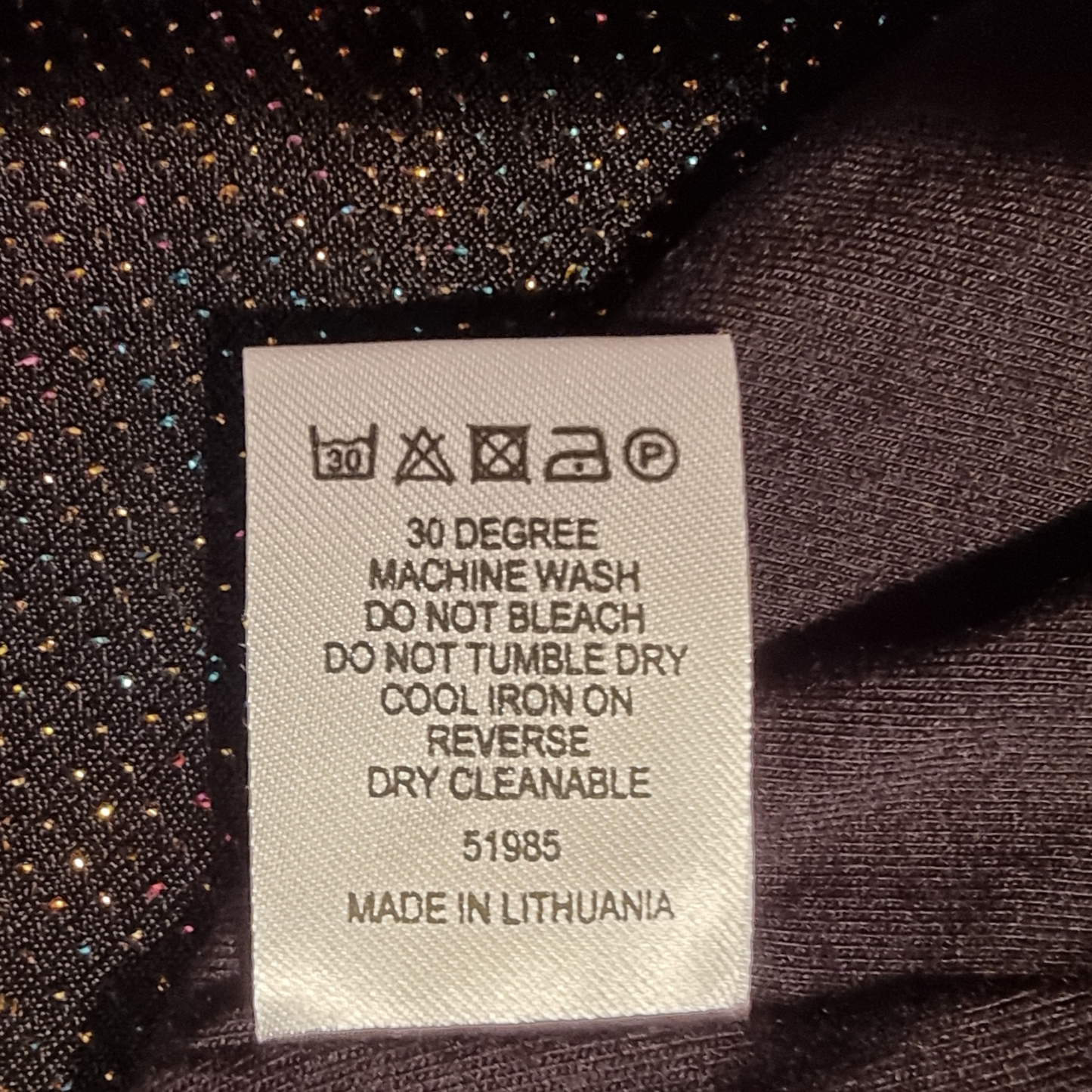Fabric tag with care instructions on a textured fabric background