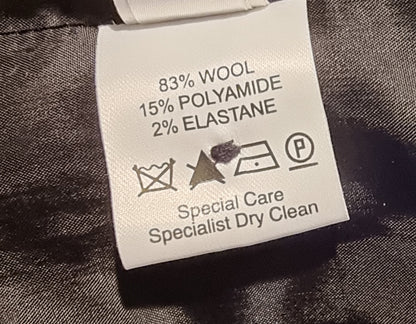 Clothing label with fabric composition and care instructions on a dark fabric background
