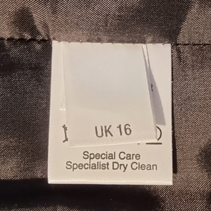 Fabric tag with size 'UK 16' and care instructions on a textured fabric background